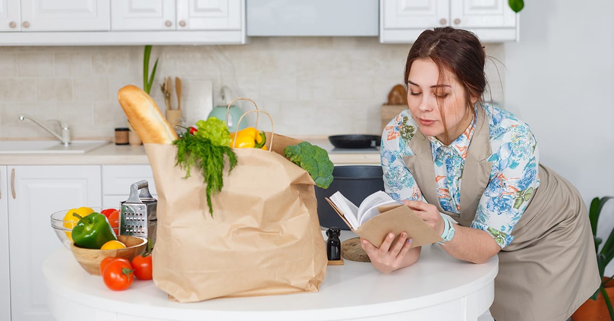 Young housewife with recipes book in the kitchen