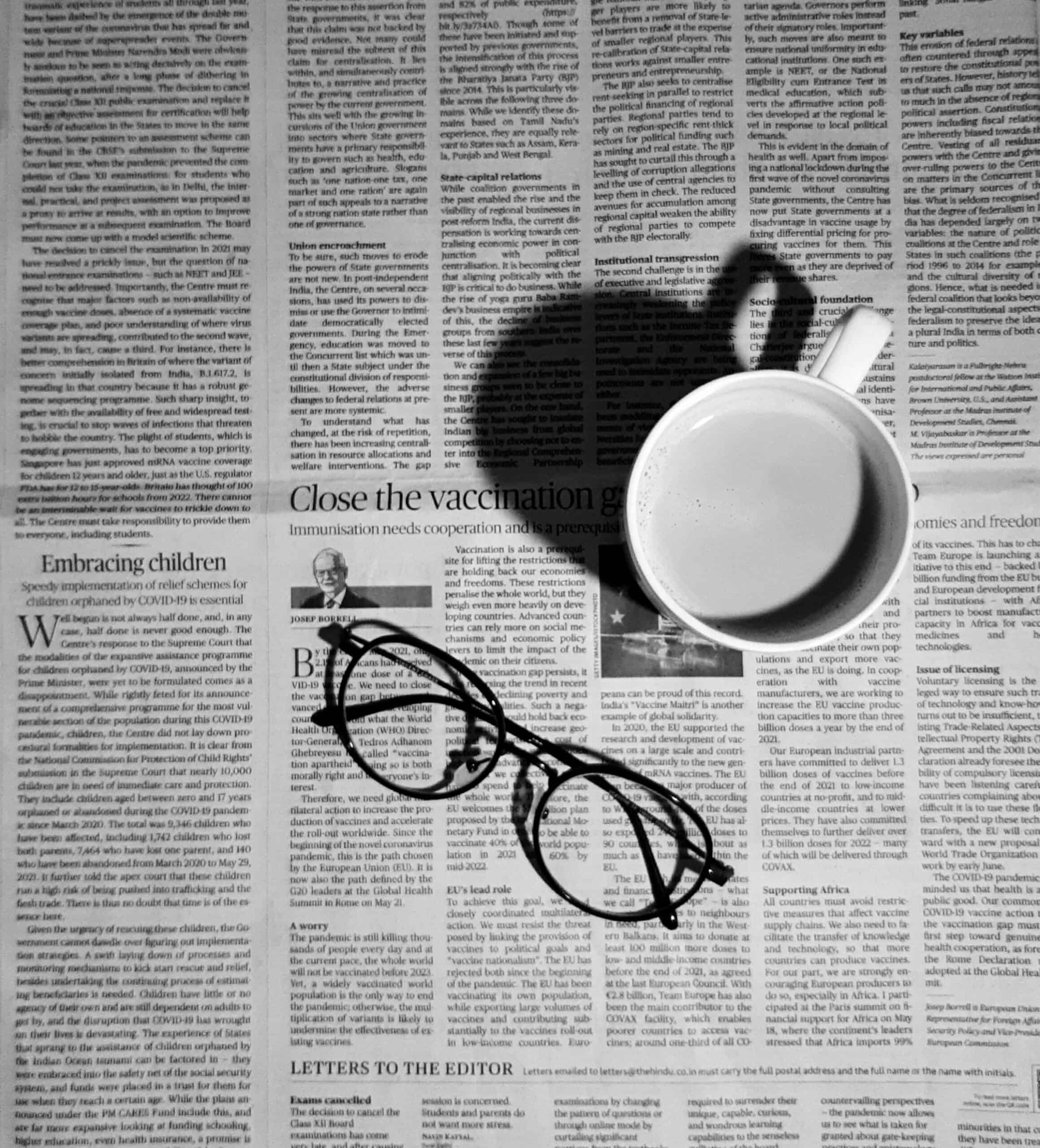 A cup of coffe and glasses on newspaper background