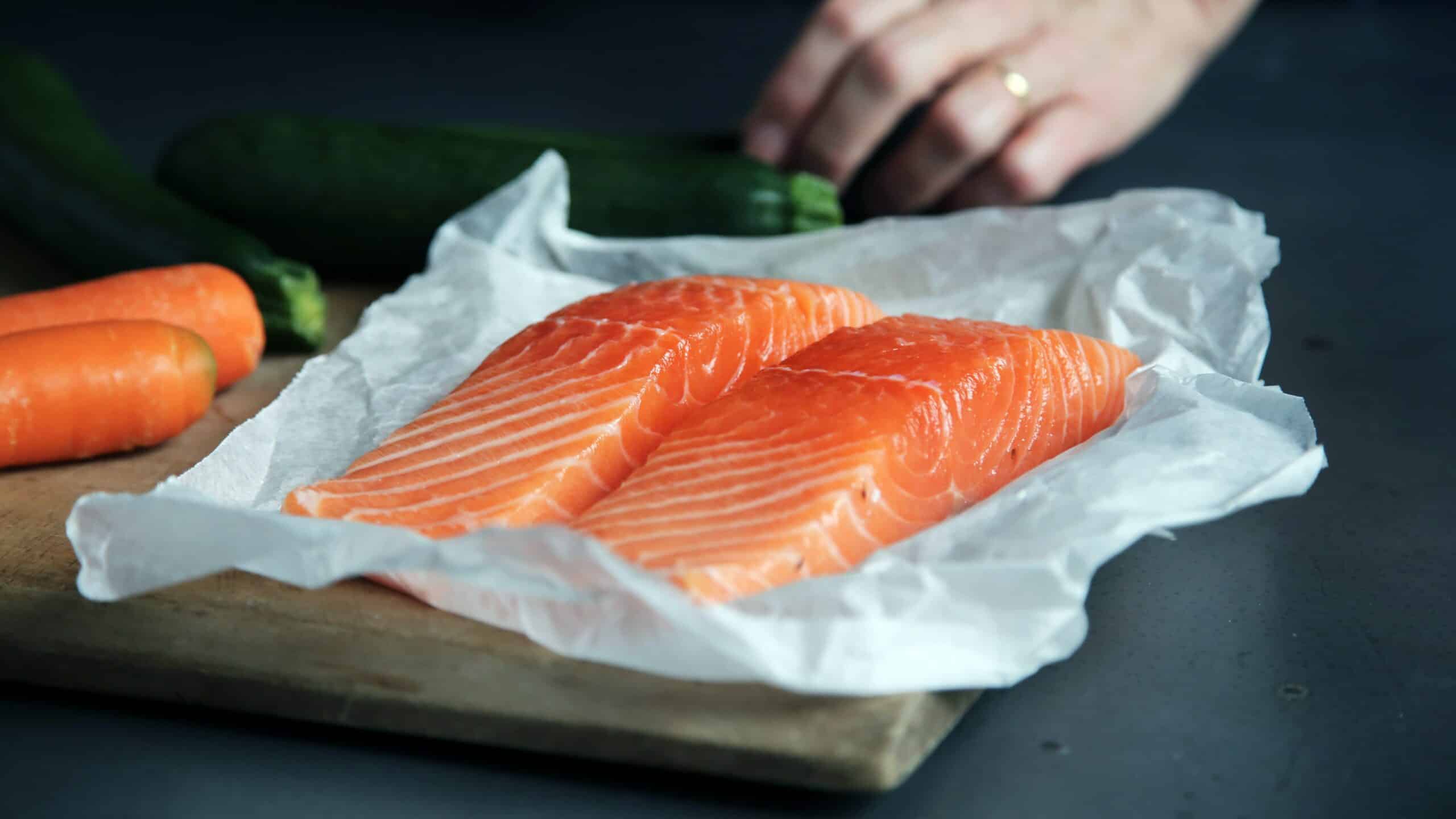 Two pieces of salmon lying on a dark background