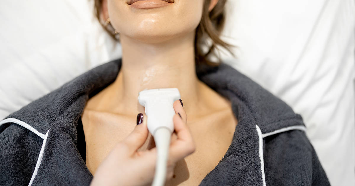 Doctor examining thyroid of female patient with ultrasound scan in medical clinic. Health and wellness concept. Close up.