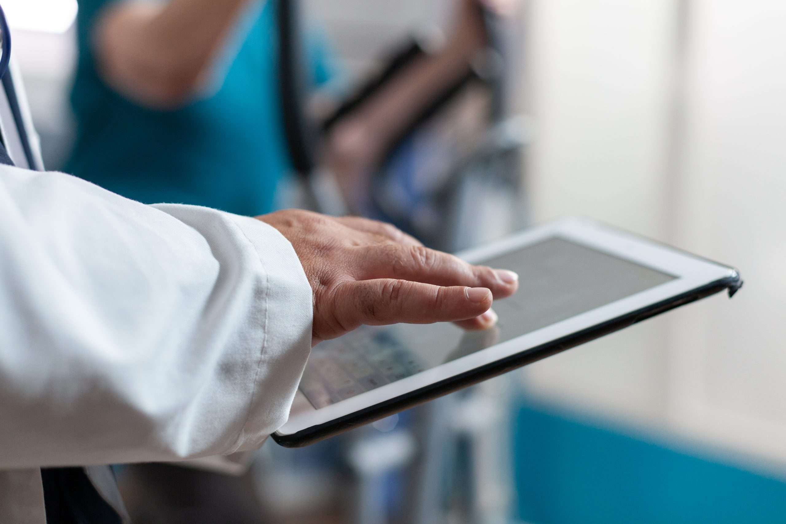 Close up of doctor using digital tablet with touch screen at physical recovery clinic. Medical worker holding modern device and technology to help patient.