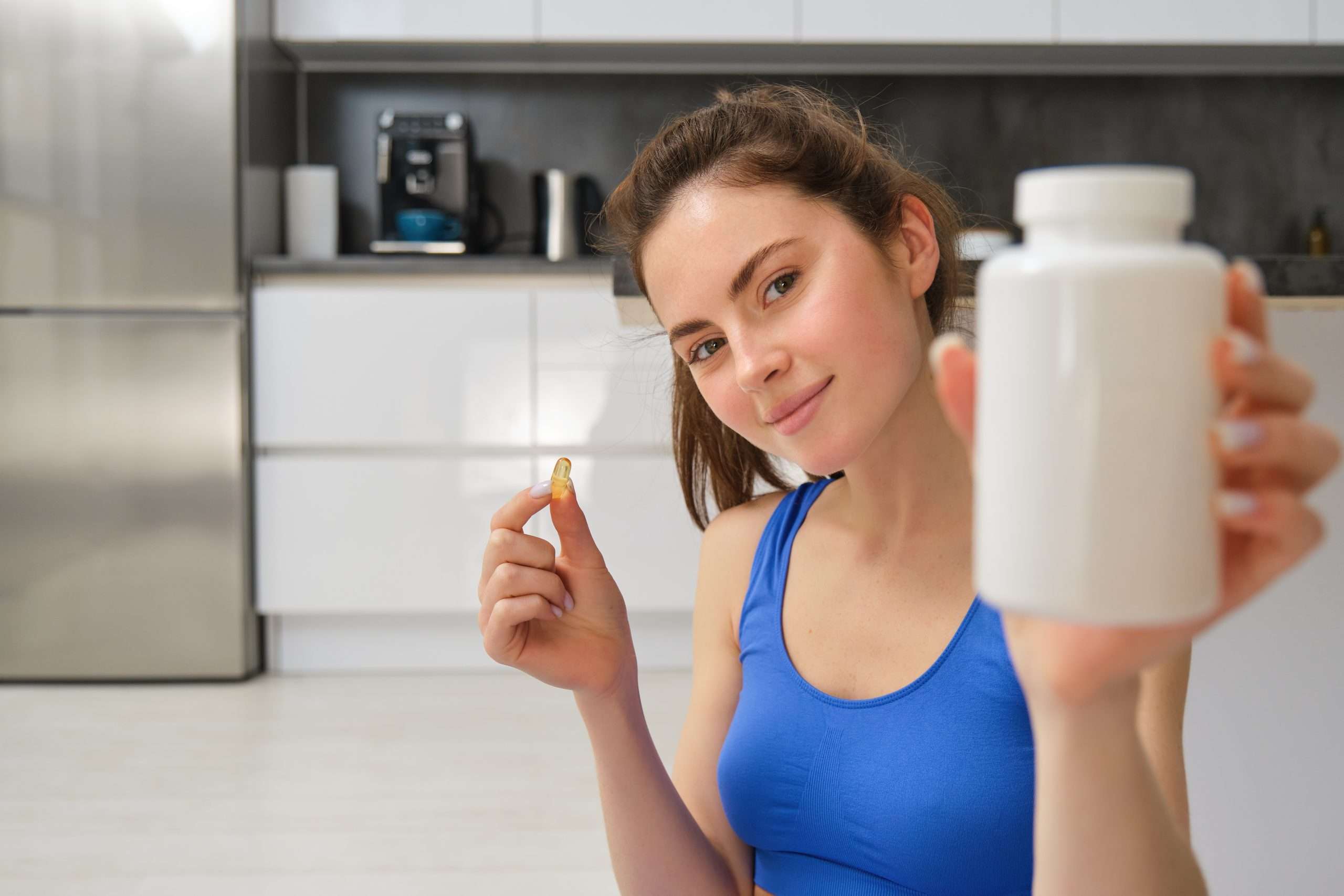 Close up portrait of young woman holding a bottle of supplements