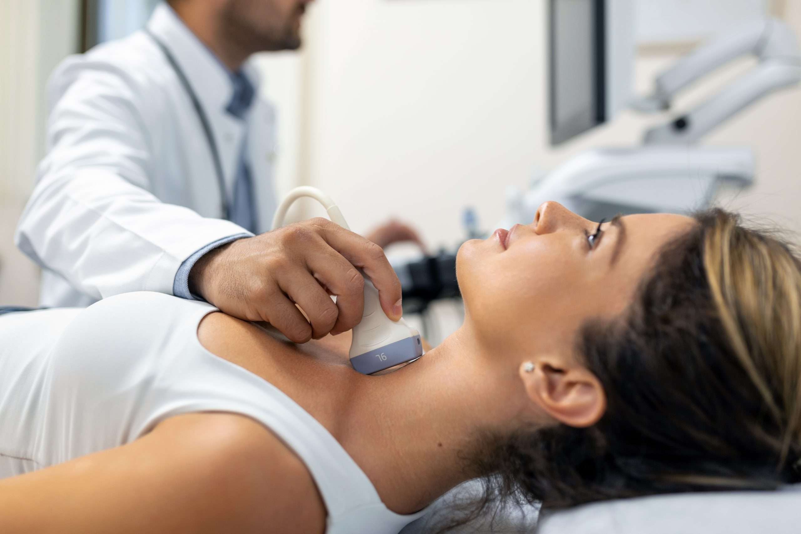 Close up shot of young woman getting her neck examined by doctor using ultrasound scanner at modern clinic