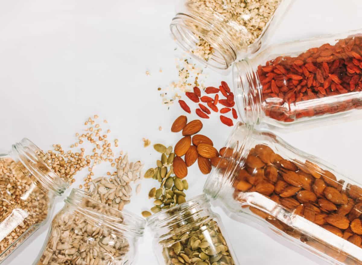 Various seeds and nuts spilling out of jars.