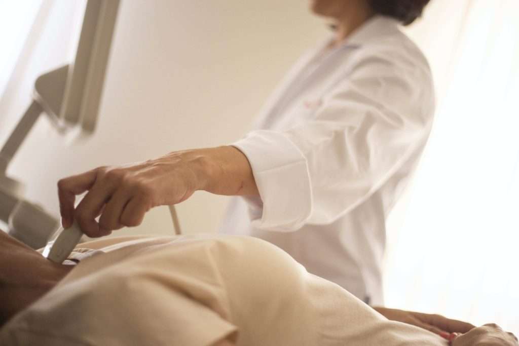 A patient on a hospital bed undergoing a neck ultrasound