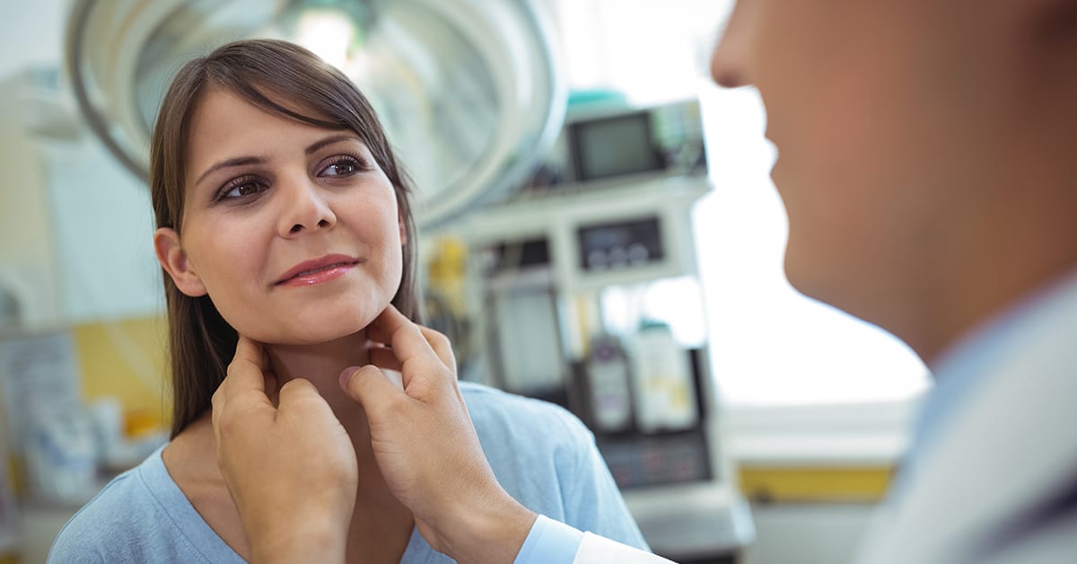 Doctor examining a female patients neck in the hospital