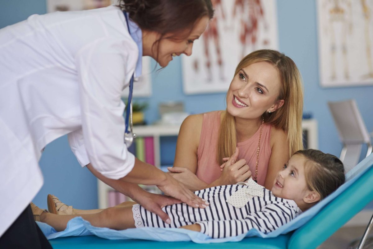 A doctor attends to a child who is with their mother